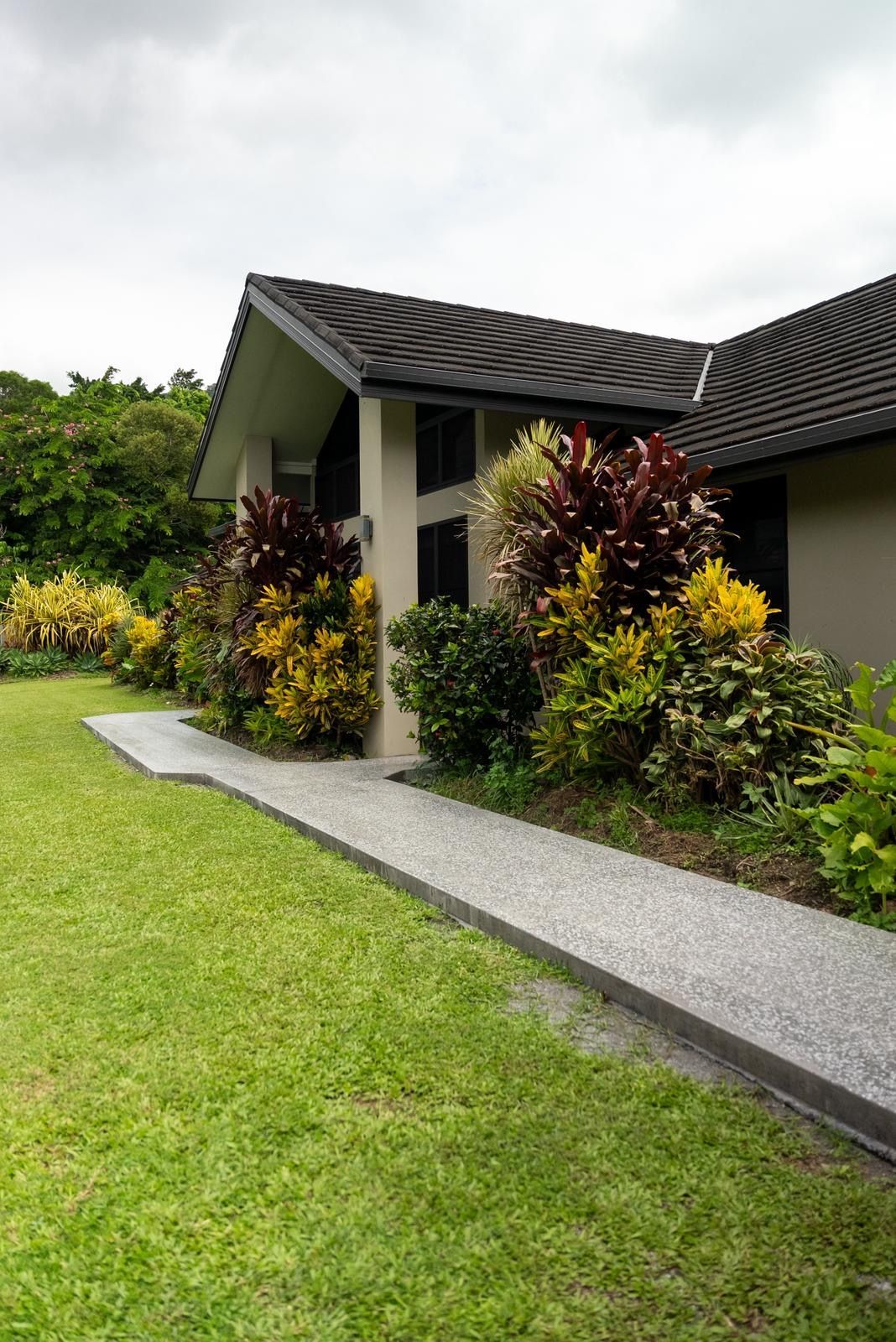 Suburban House With Dark Roof, Front Garden, and a Concrete Walkway Beside a Green Lawn — All Grind & Coat in Cairns, QLD