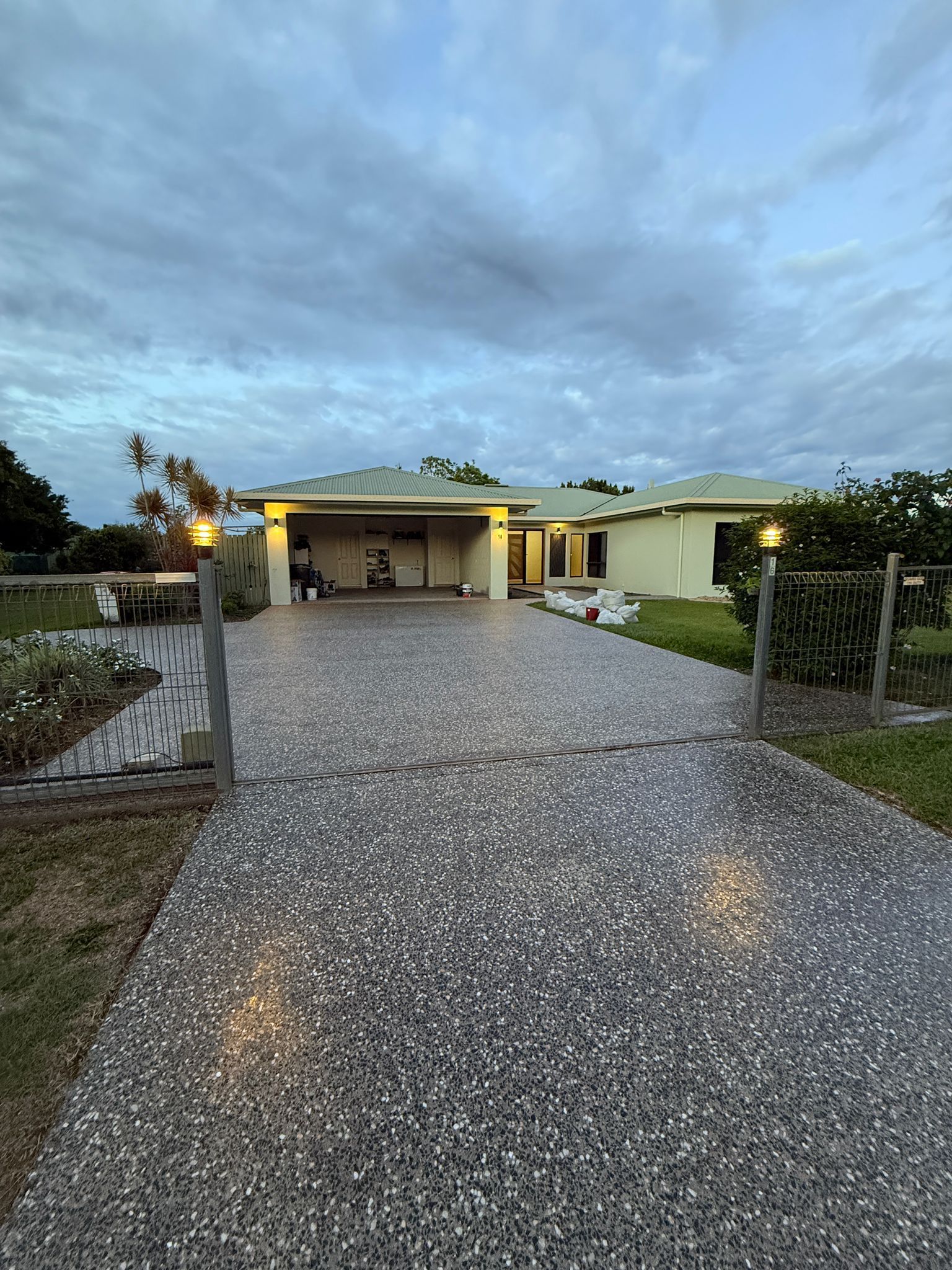 Lit Gravel Driveway Leading to a Single-story House at Dusk Under a Cloudy Sky — All Grind & Coat in Cairns, QLD