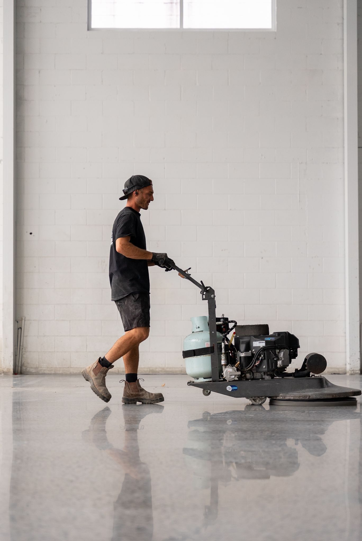 Worker Operating a Floor Polishing Machine in a Bright Empty Room — All Grind & Coat in Cairns, QLD