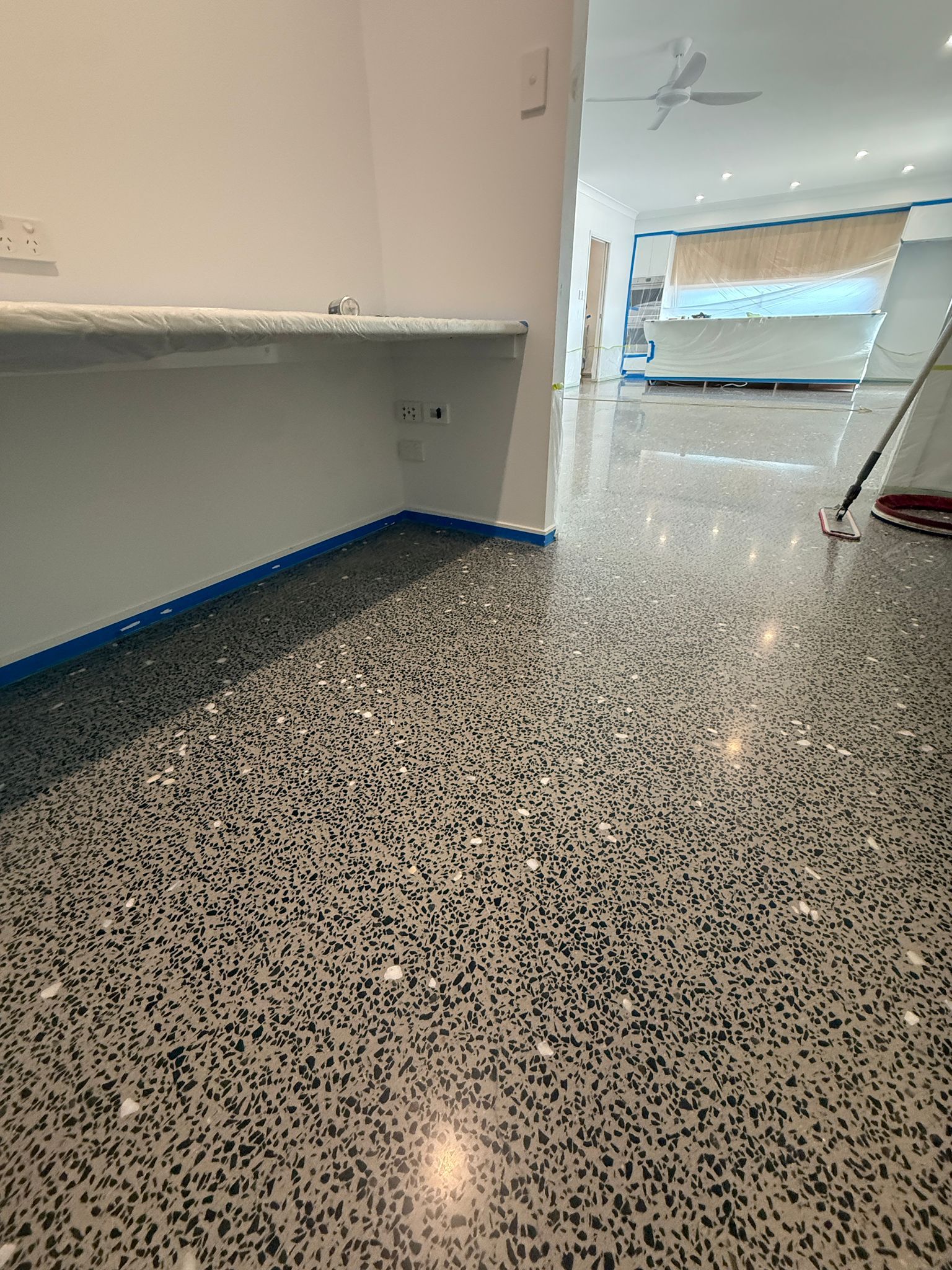 Empty Room With Speckled Floor, White Walls, and Blue Painter’s Tape Along the Baseboards — All Grind & Coat in Cairns, QLD