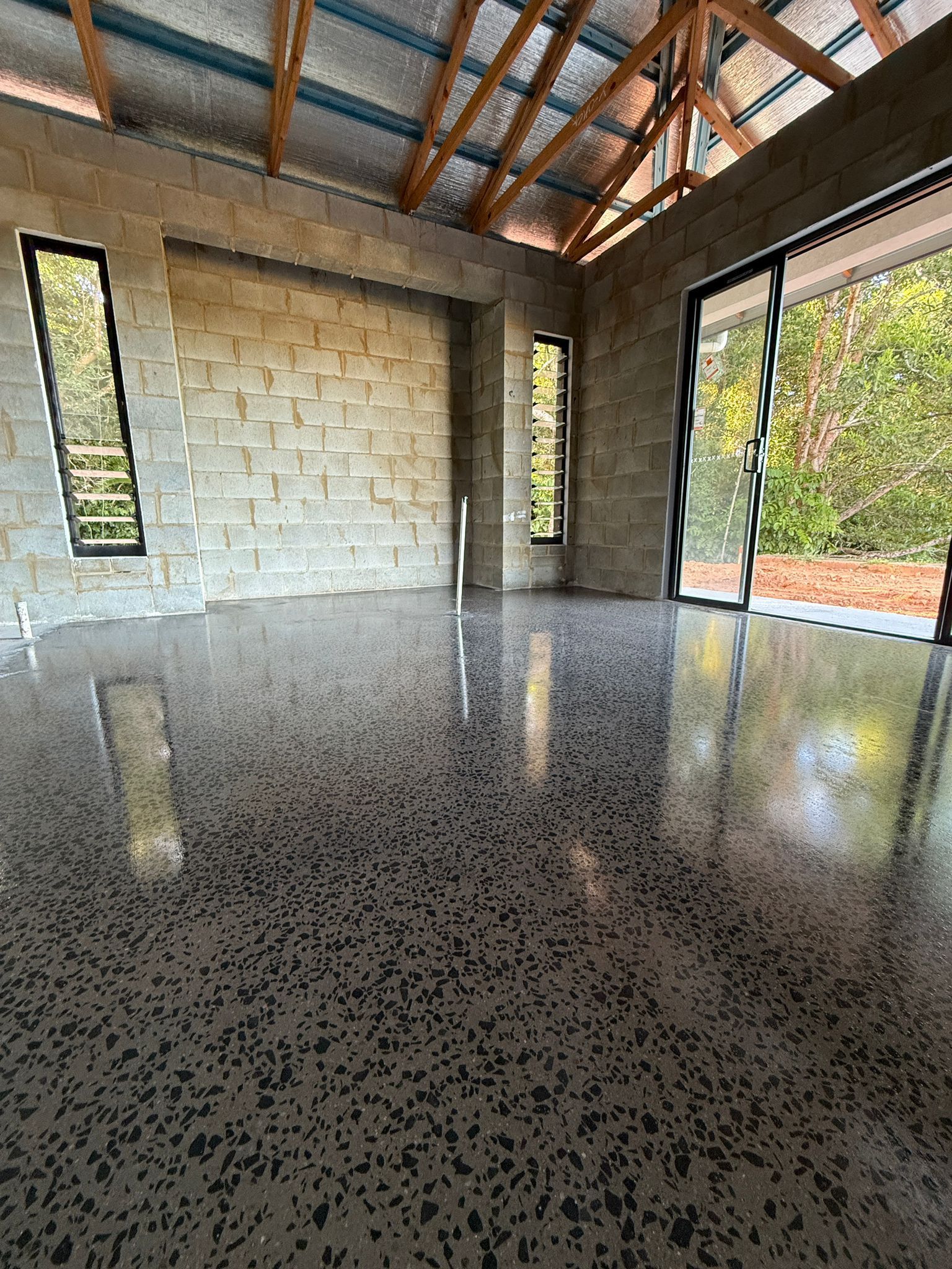 Empty Unfinished Room With Speckled Concrete Floor, Cinderblock Walls — All Grind & Coat in Cairns, QLD