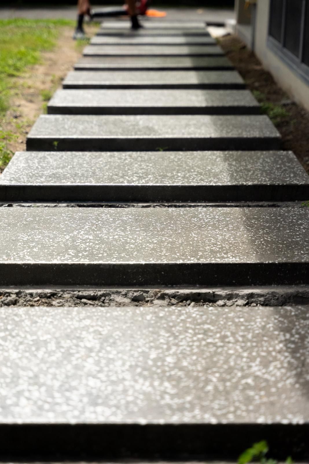 Stepping Stones Across a Sunlit Garden Path Beside Grass and a Building — All Grind & Coat in Cairns, QLD