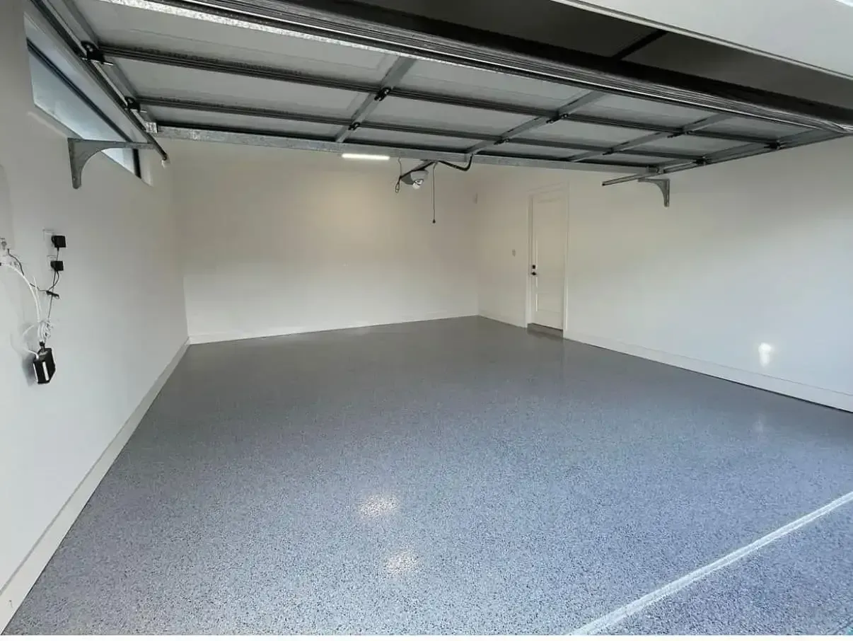 Empty Garage With Open Door, Grey Floor, White Walls, and Exposed Ceiling Beams — All Grind & Coat in Tablelands, QLD