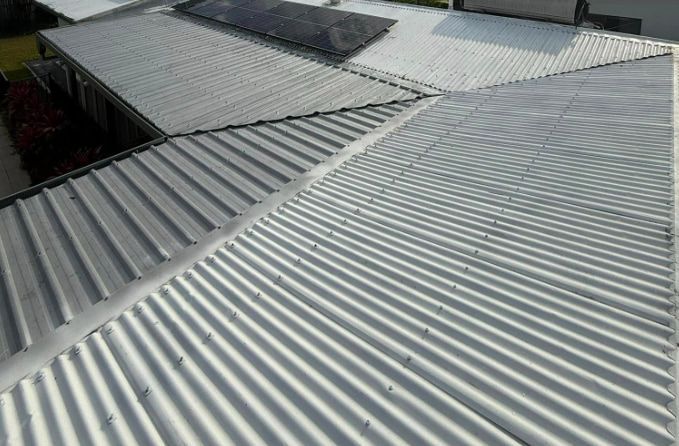 A White Corrugated Metal Roof With Solar Panels on It — All Grind & Coat in Cairns, QLD