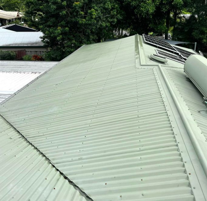 A Green Corrugated Metal Roof With Solar Panels on It — All Grind & Coat in Cairns, QLD