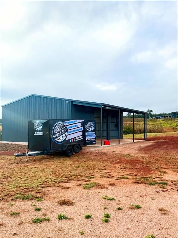 Black Trailer Beside a Metal Shed on a Red Dirt Lot Under a Cloudy Sky — All Grind & Coat in Tablelands, QLD