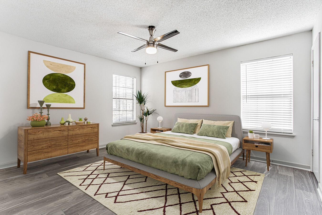 Bright bedroom with a bed, wood dresser, framed art, two windows, and a ceiling fan.