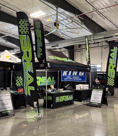 Trade show booth with neon green “REAL” banners and a blue “KING” sign in an industrial hall