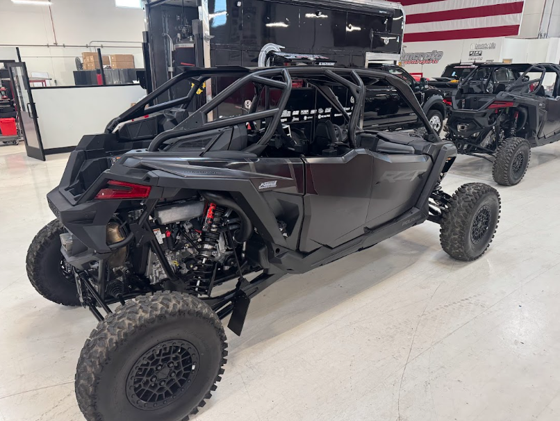 Black off-road side-by-side vehicle in a garage with an American flag in the background