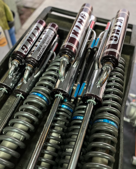 Close-up of four black and silver coilover shock absorbers with blue adjusters