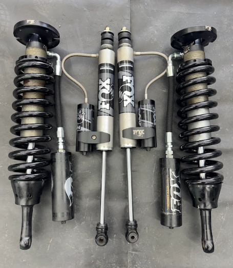 Set of black performance suspension shocks and coilovers arranged on a gray background