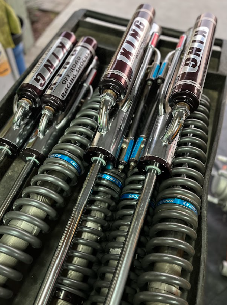 Close-up of bundled clear springs with silver-and-red labeled tubes, stacked on a shelf.