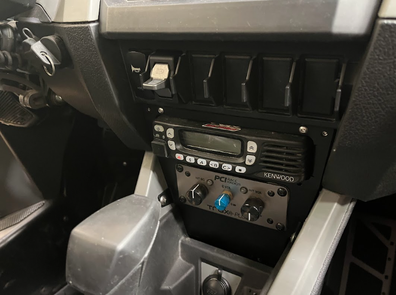Vehicle center console with two-way radio and control panel, black and gray interior