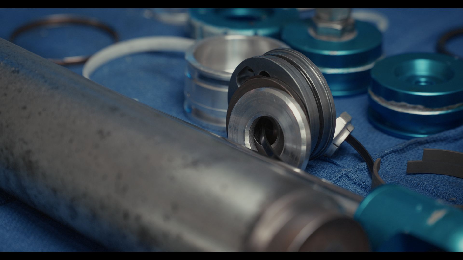 Blue and silver fitness jump rope handles on a blue surface, with the cable in the background