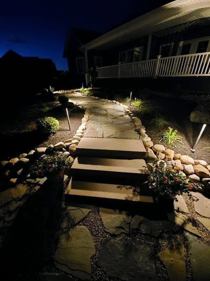 Illuminated stone steps leading up a dark garden path beside a house at night