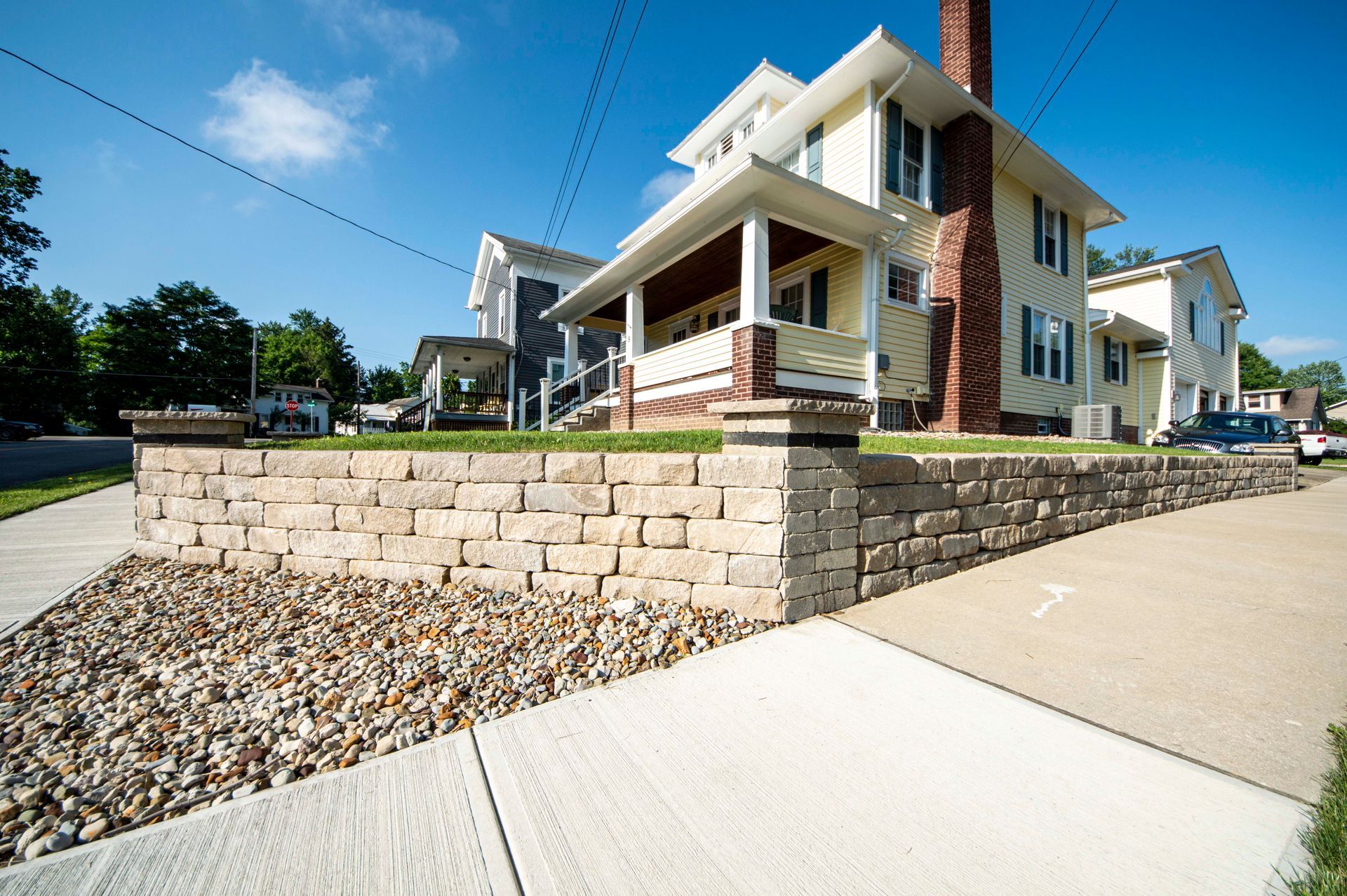 Modern apartment building with stone retaining wall, sidewalk, and blue sky