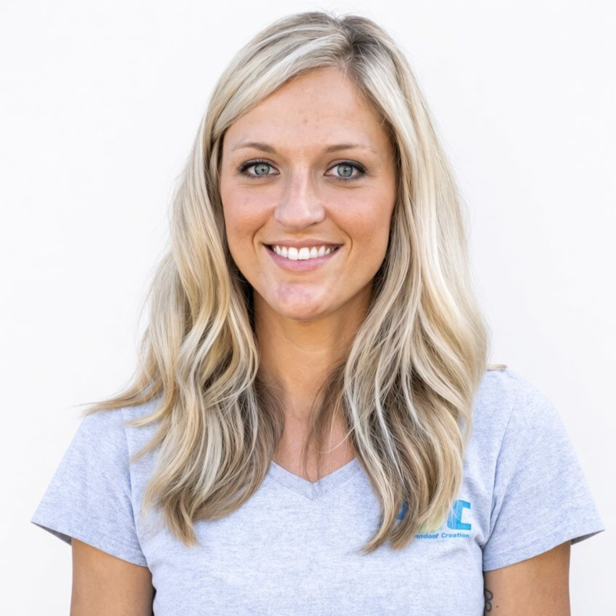 Smiling blonde woman in a light gray T-shirt against a white background
