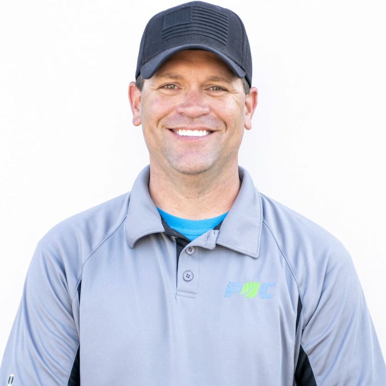Smiling man in a dark cap and gray polo shirt against a white background