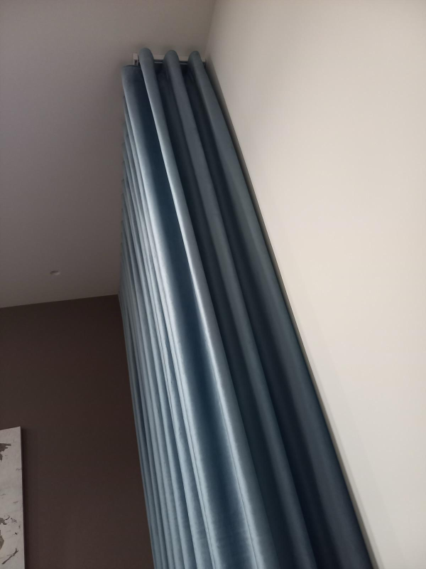 Tende blu appese accanto all’angolo tra una parete bianca e il soffitto