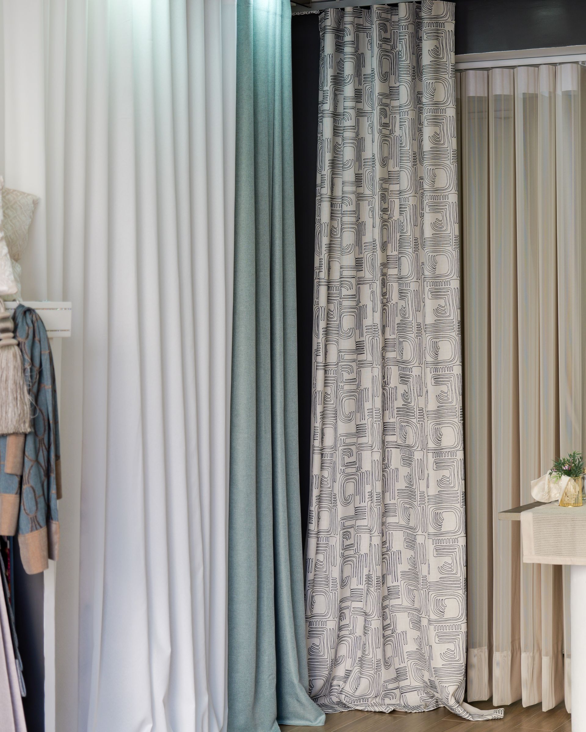 Tende assortite appese, in bianco, blu, grigio e beige, esposte in uno showroom