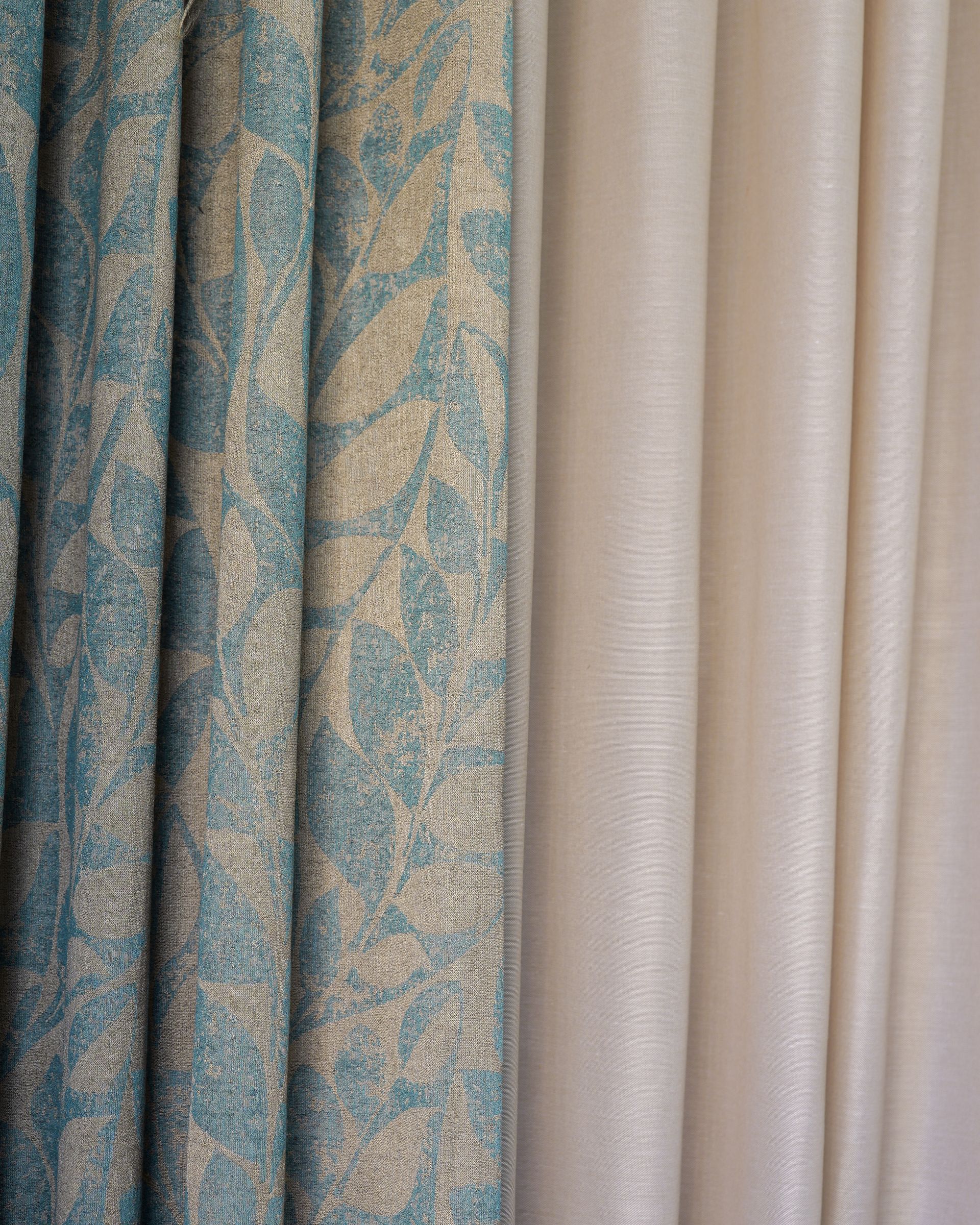 Tenda blu a fantasia accanto a tende velate beige