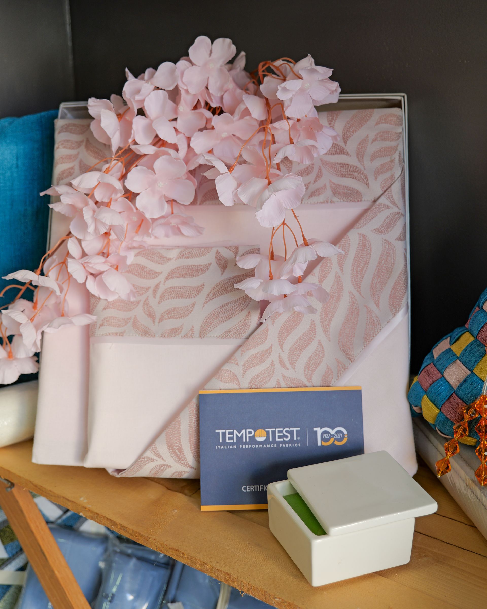 Scatole regalo rosa con carta velina, un piccolo biglietto blu e una scatola bianca su uno scaffale