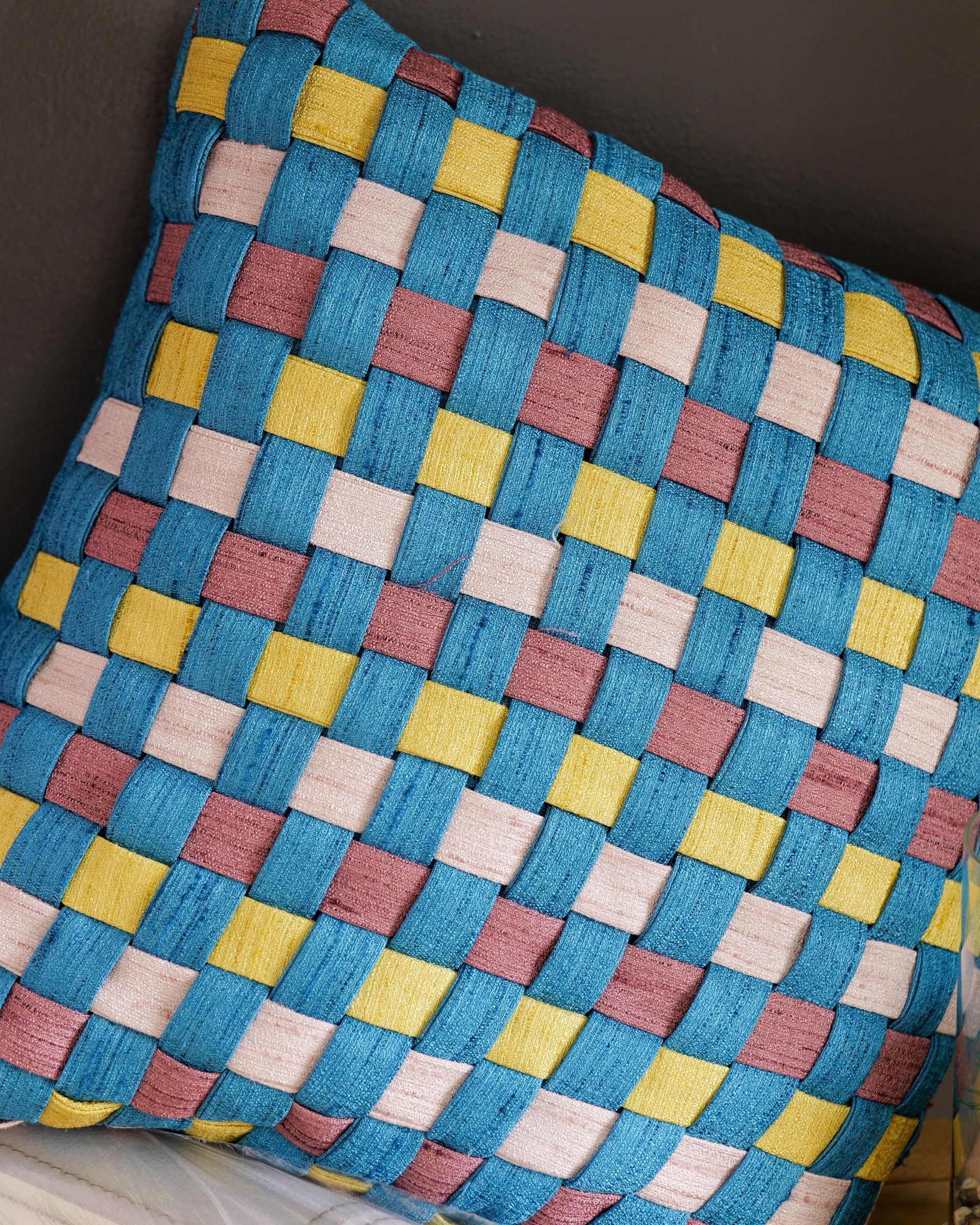 Cuscino intrecciato colorato con motivo a quadri blu, rosa, giallo e verde acqua