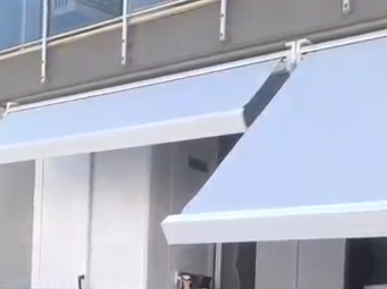 Tende blu sopra le vetrine sulla facciata di un edificio