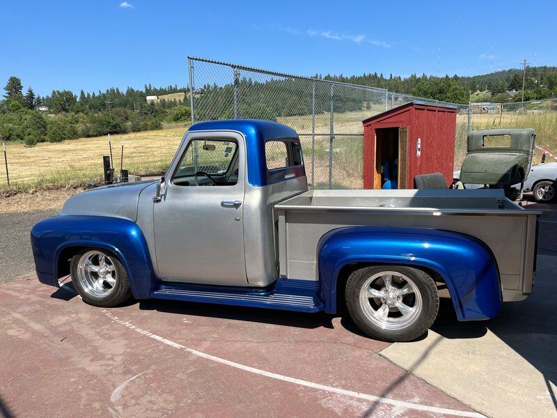 A silver and blue truck is parked on the side of the road.