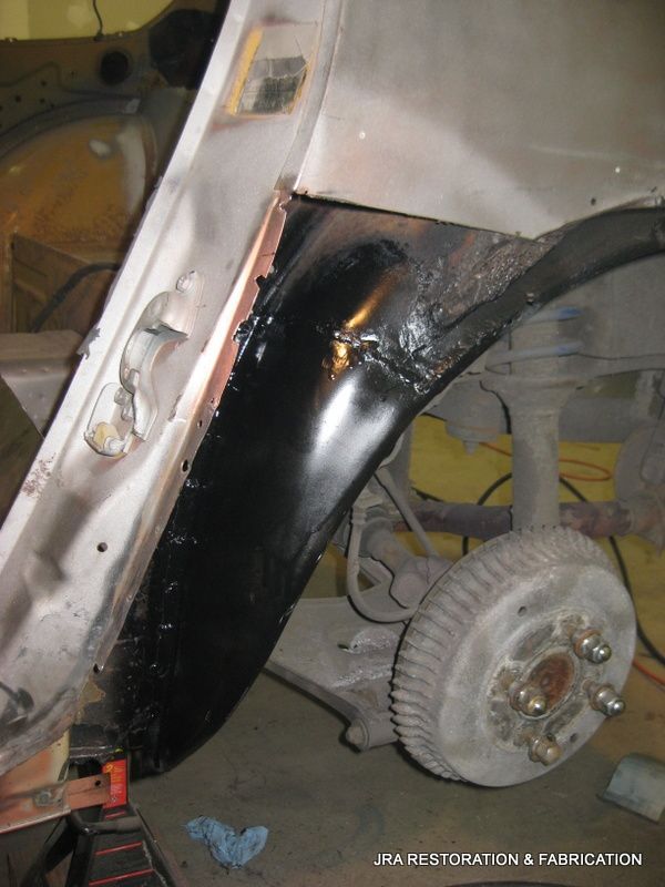 A white car with a black fender and a wheel