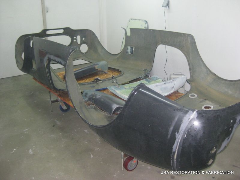 A car body is sitting on a cart in a garage.