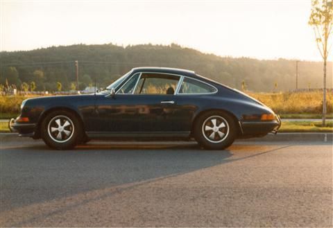 A blue porsche is parked on the side of the road