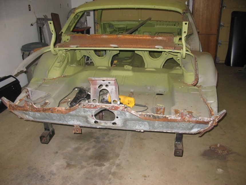 A green car is being built in a garage