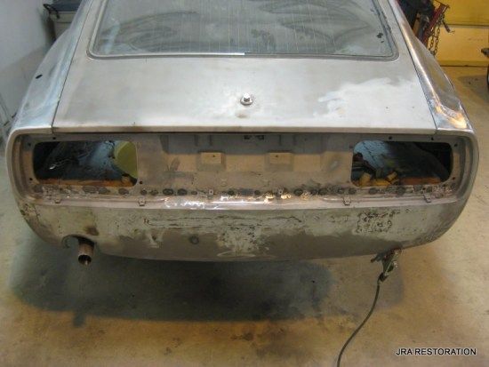 The rear end of a silver car is being worked on
