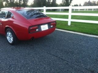 A red car is parked next to a white fence