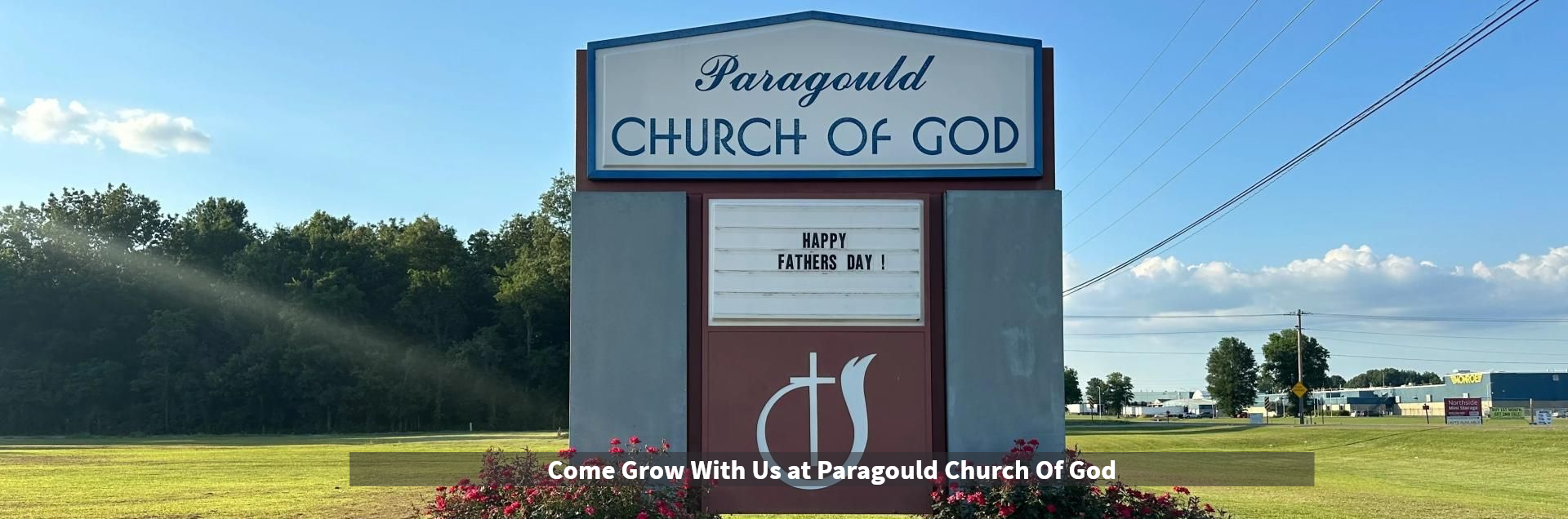 Small church sign reading “Fellowship Church of God” in a grassy field under a blue sky.