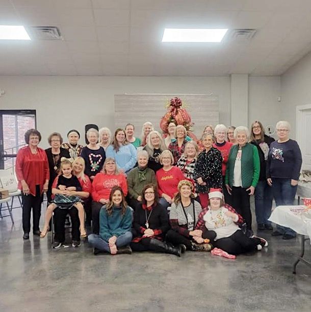 Group of people posing indoors at a holiday gathering, with festive red and green clothing and decorations