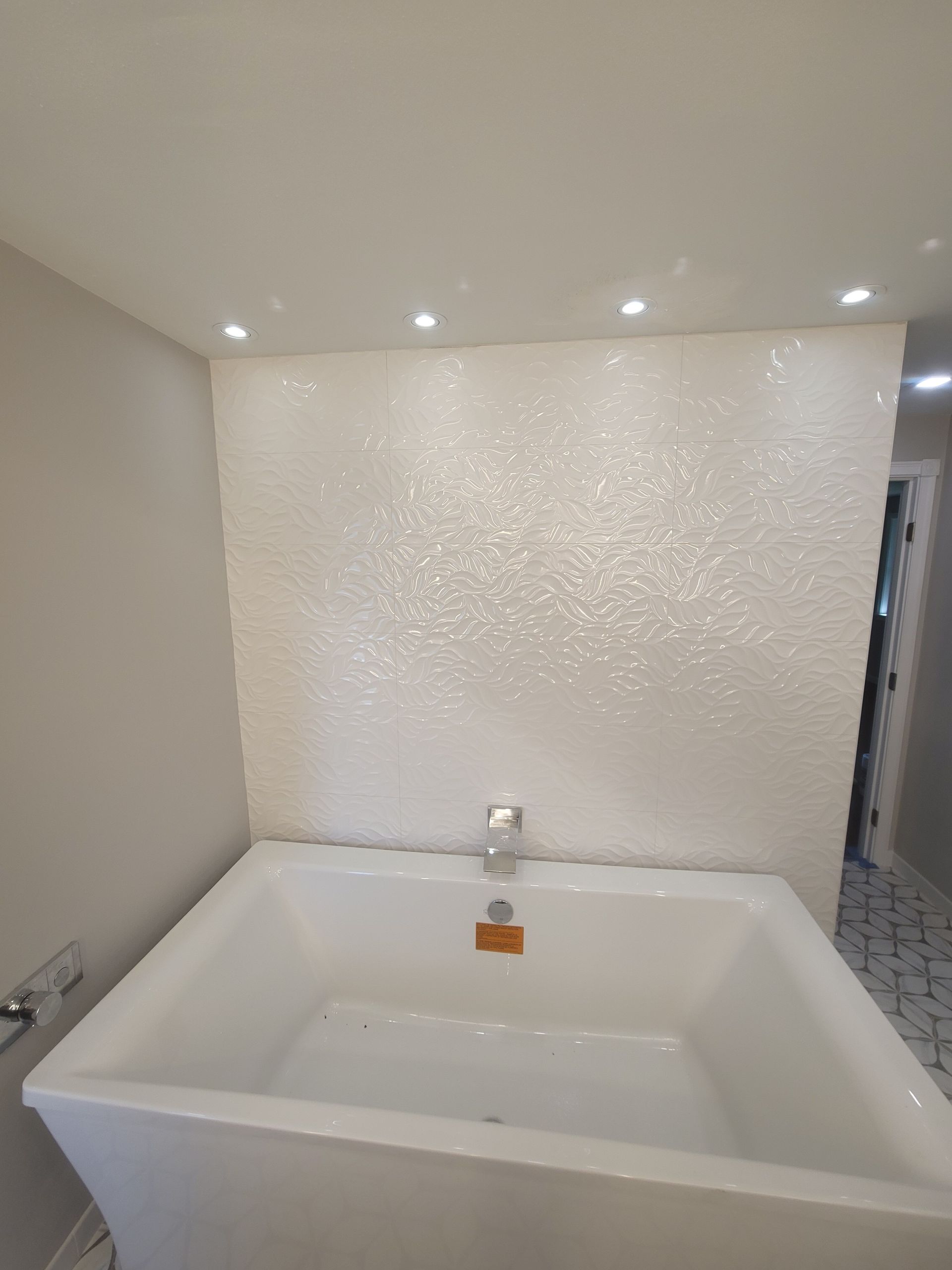 A white bathtub is sitting in a bathroom next to a white wall.