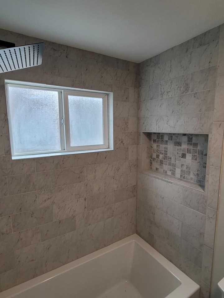 A bathroom with a bathtub and a window.