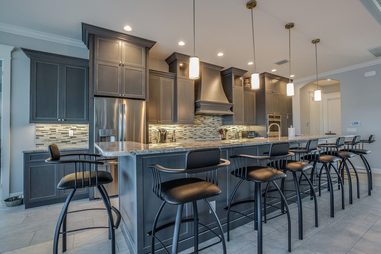 A living room with hardwood floors and a kitchen in the background.