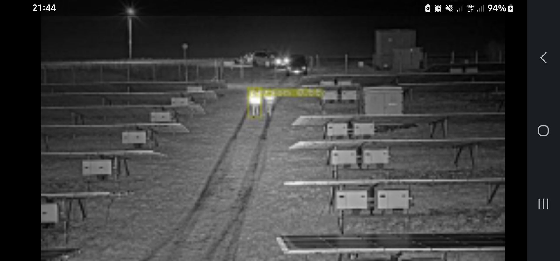 Een bouwplaats 's nachts met onverharde paden en rijen banken of afzettingen onder verlichting.