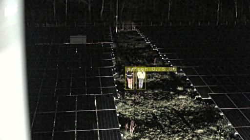 Donkere zonnepanelen 's nachts, met iemand die met een zaklamp schijnt op een grasstrook tussen de rijen.