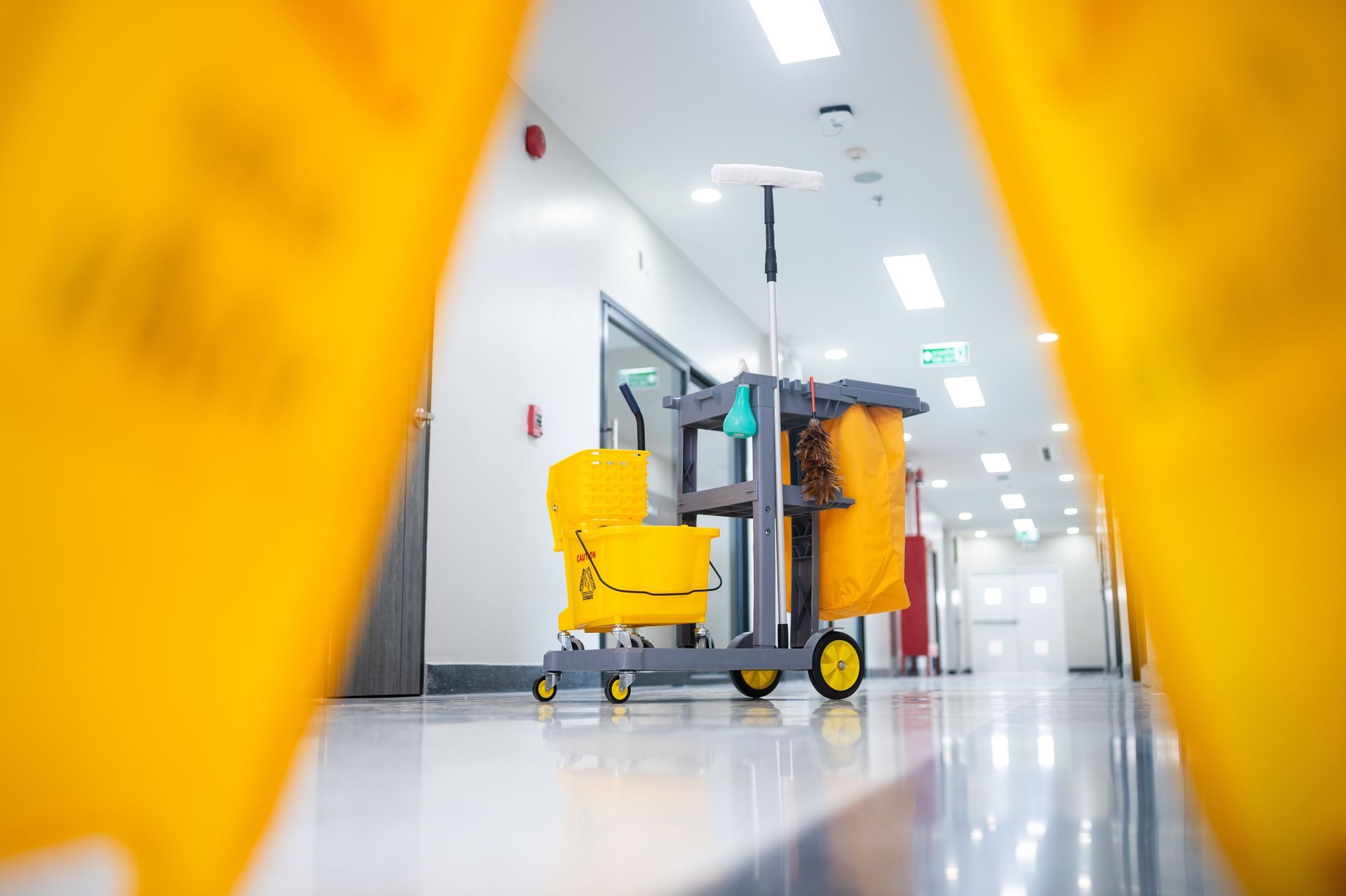 Janitor cart with yellow cleaning supplies in a bright hospital hallway