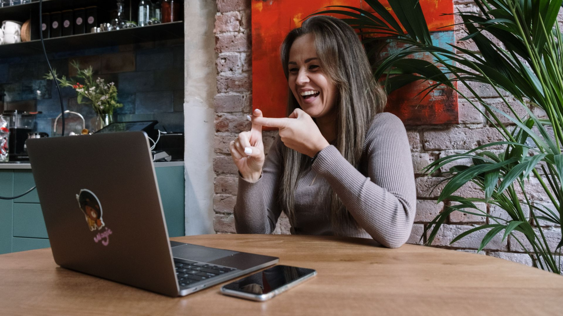 Woman signing on a laptop video call during an online ASL therapy session at home