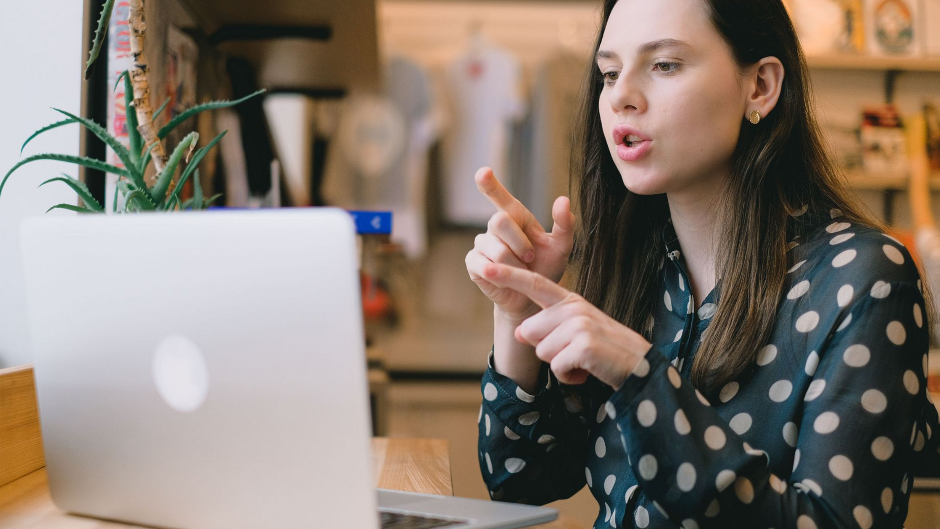 Woman signing in American Sign Language during a video call on her laptop at home