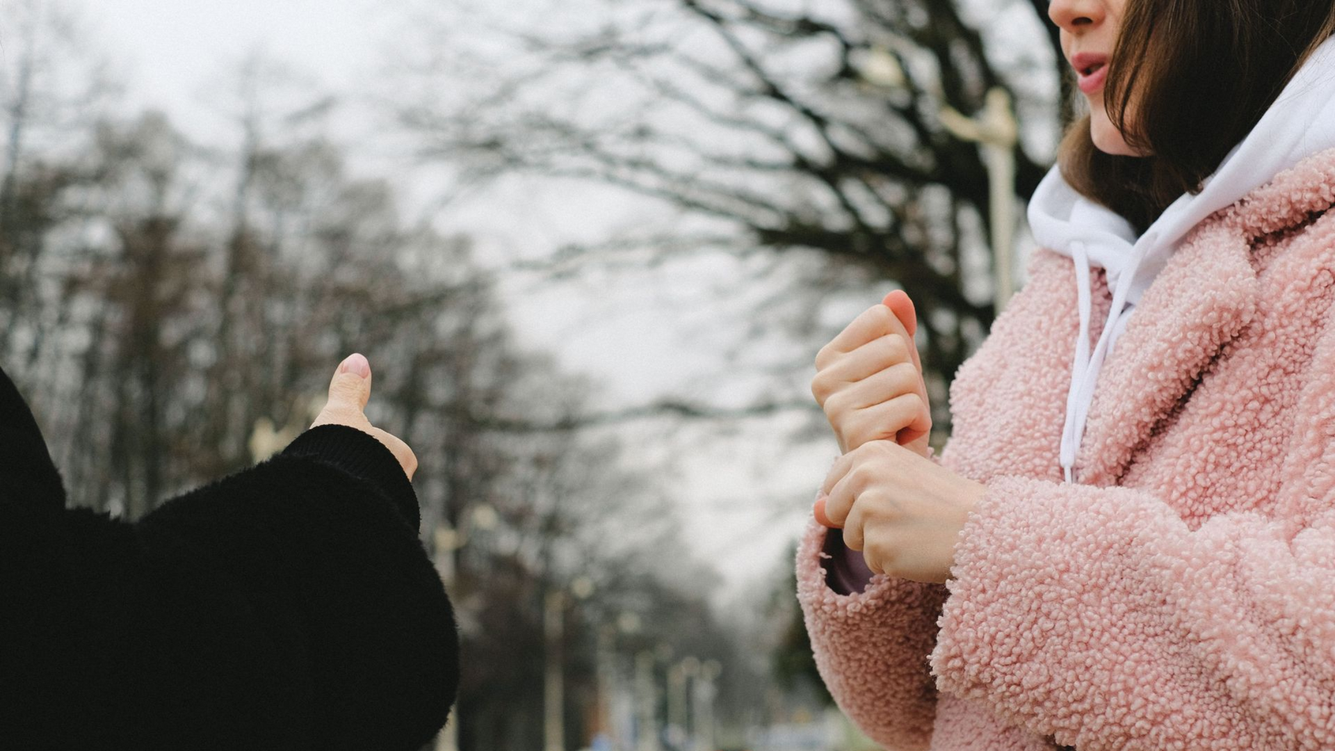 Two people signing in American Sign Language during a conversation outdoors in winter