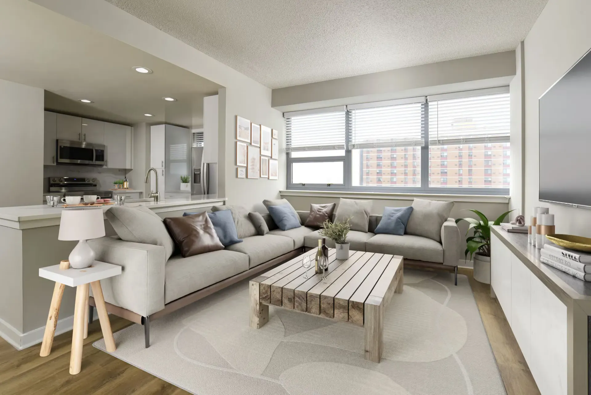 Open-concept living room with a light gray sofa, wooden coffee table, and modern kitchen.