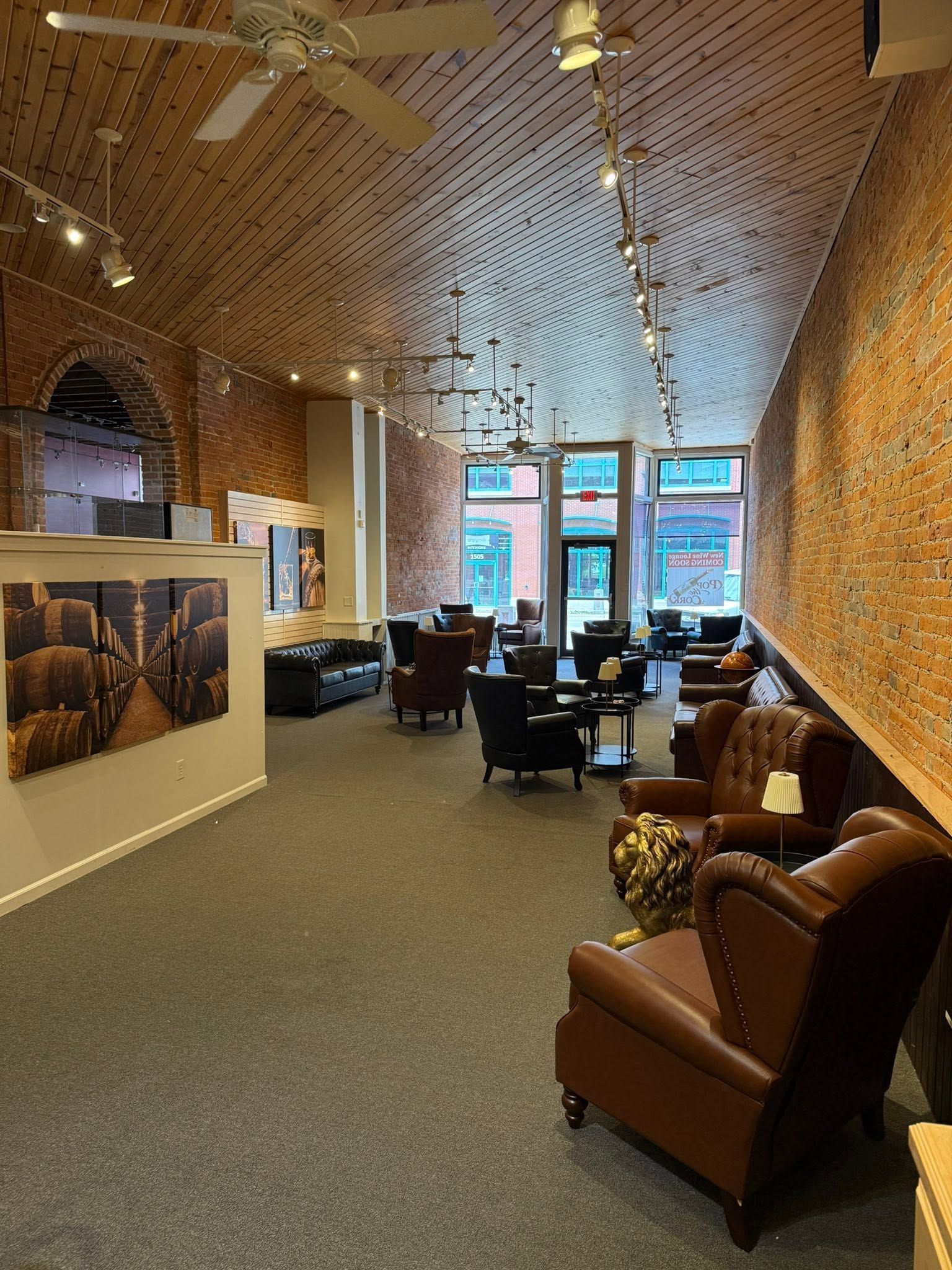 Cozy lounge with leather chairs, patterned walls and ceiling, and large windows at the far end.