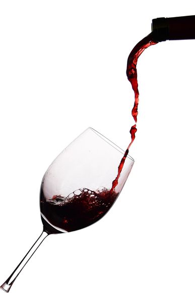 Wine pouring into a tilted glass against a white background
