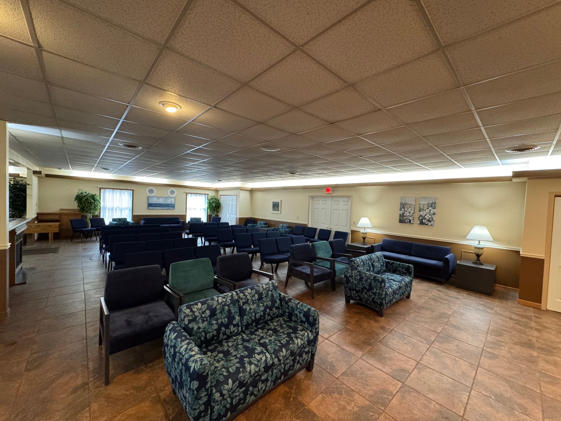 Quiet lounge with patterned armchairs, sofas, and warm ceiling lights on a tiled floor